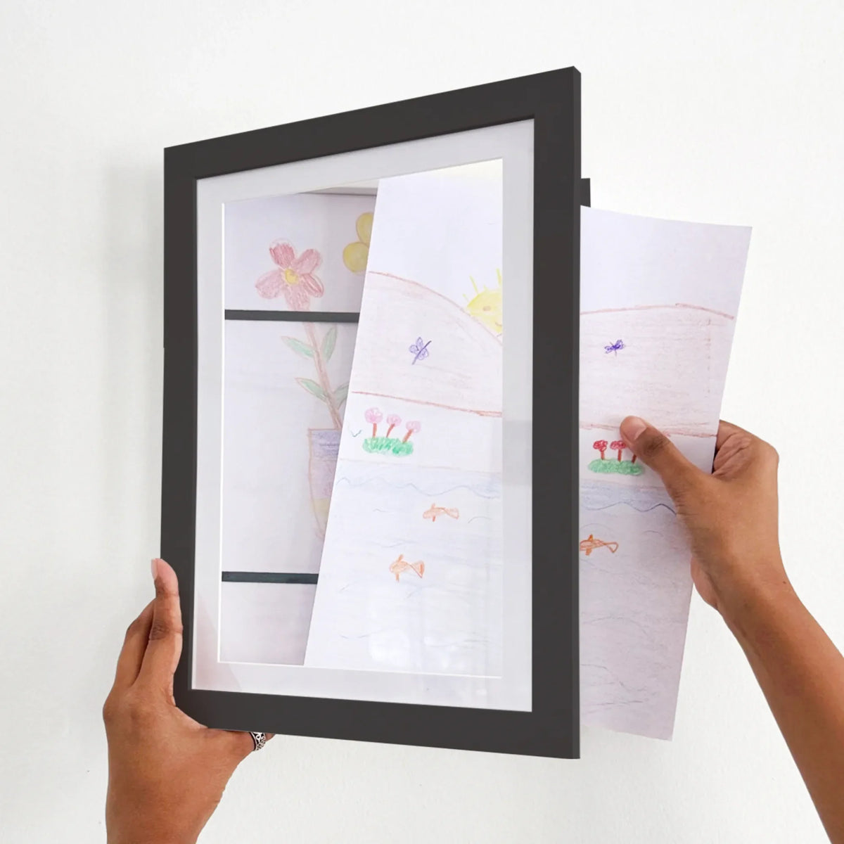 A person holds a reusable, art frame that can hold upto 70kids artworks and photos.