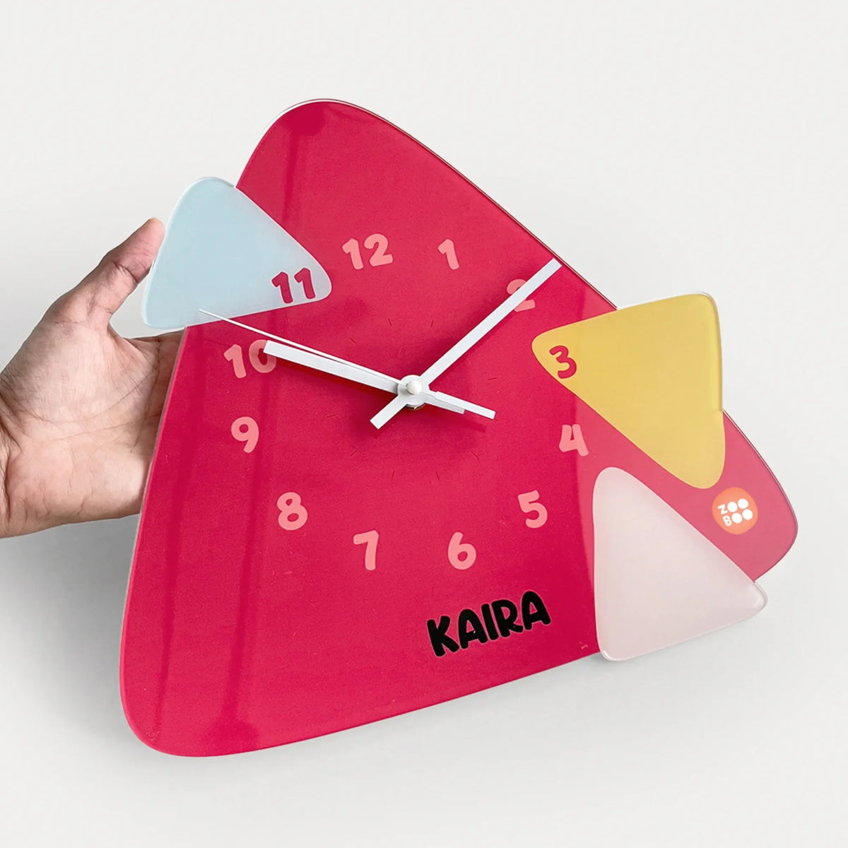 A hand holds a personalized  triangular wall clock with an abstract design.