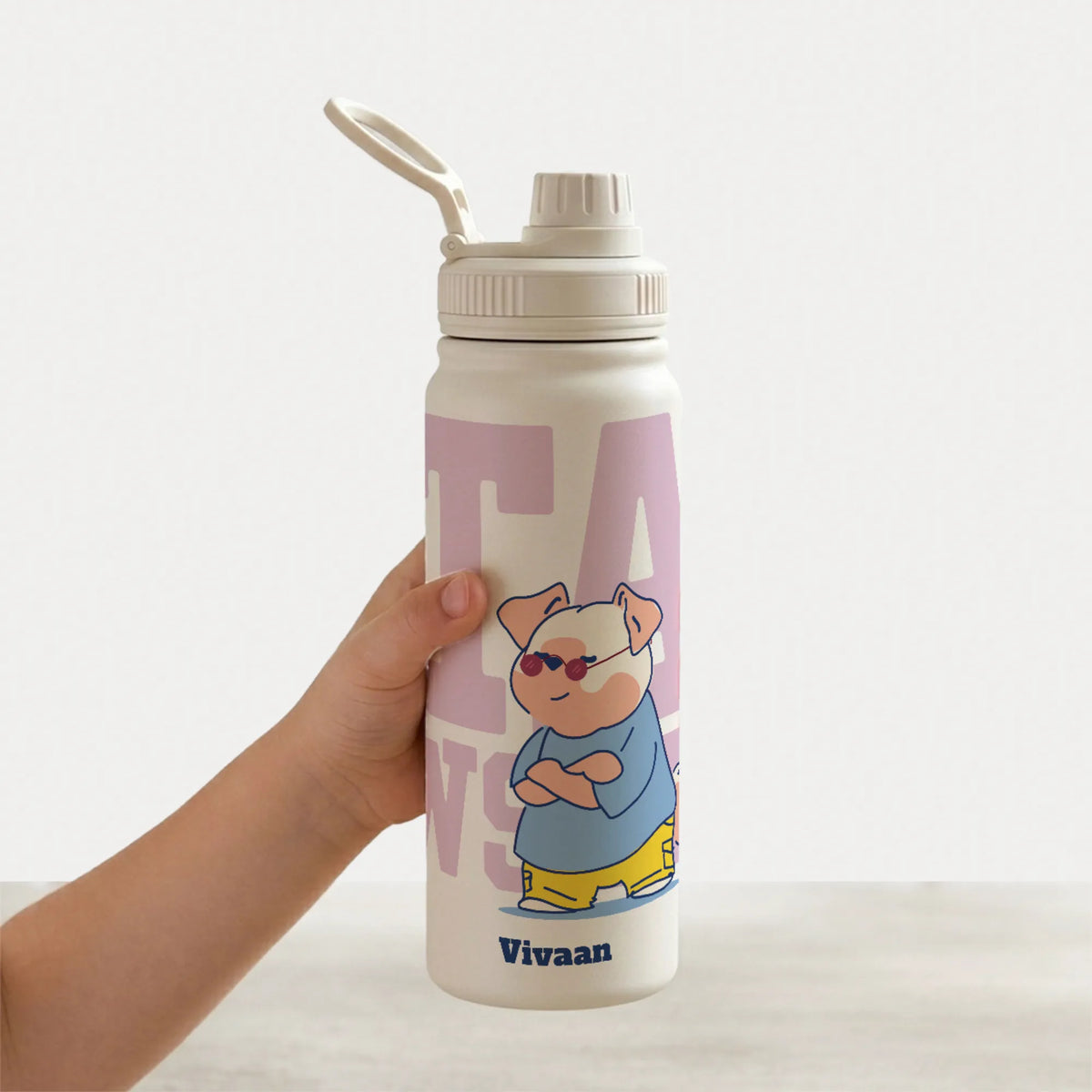 A hand holding a staniless steel, leakproof,  water bottle with an egonomic handle. The bottle features a cartoon illustration of a cute and cool dog wearing sunglasses and a blue shirt.
