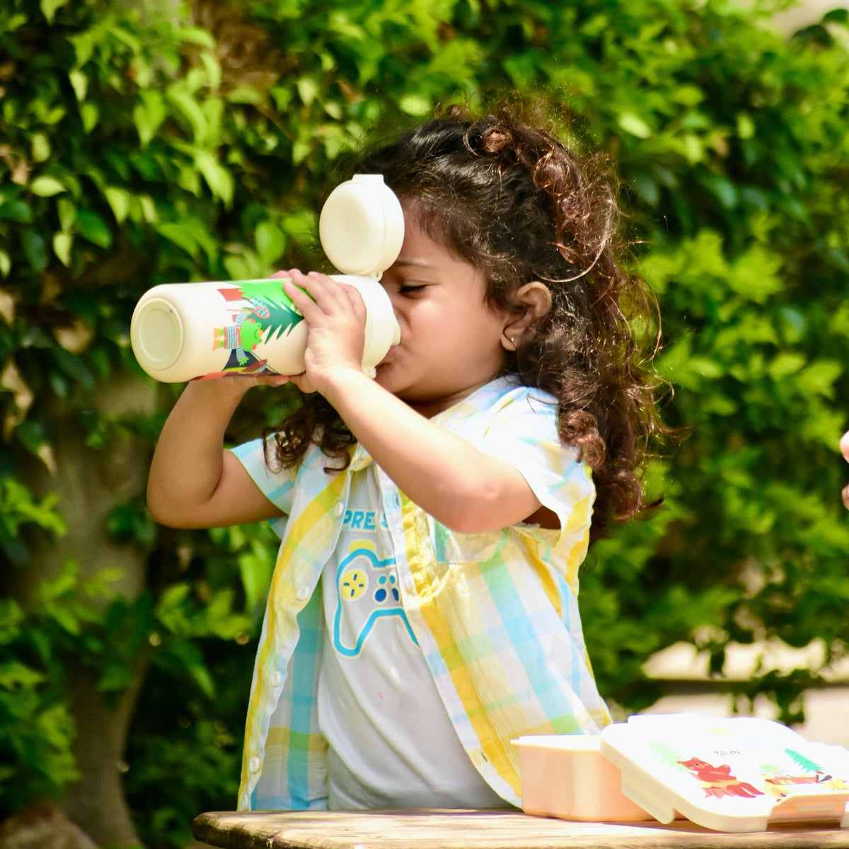 A young child drinking from a personalized insulated water bottle.