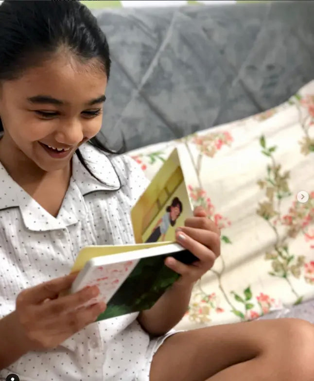 A young girl smiling while reading a personalized zooboo book.